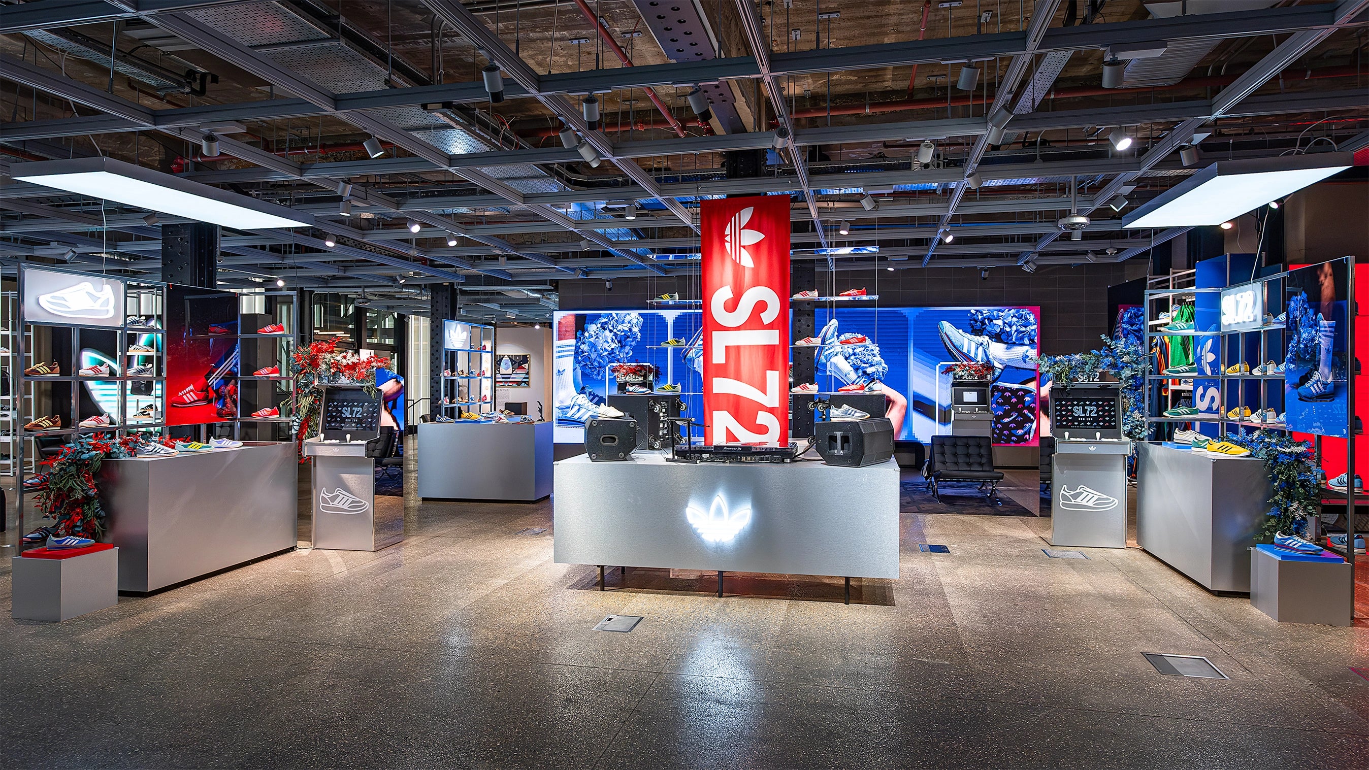 A broad view of the Adidas Bond Street store SL72 collection event, highlighting the many floral installations by Event Florist Amaranté London. The bespoke store decoration décor includes red and blue floral accents, creating a vibrant backdrop for Adidas products.