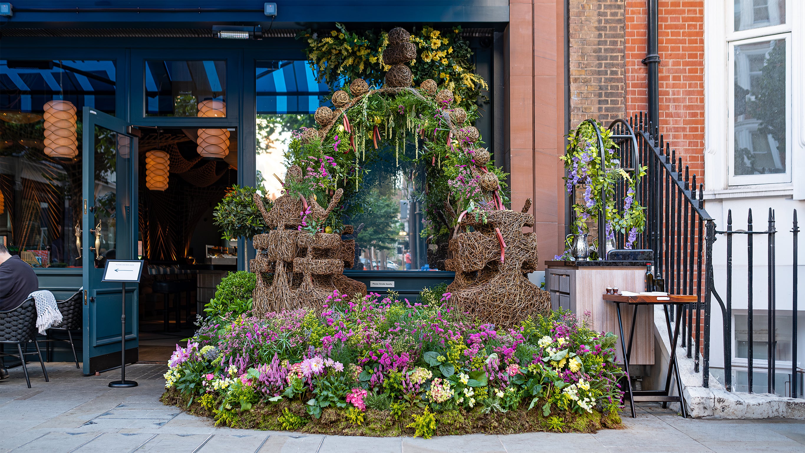 Image of a stunning floral arrangement for Chelsea in Bloom, features a mix of wicker balls, green foliage, and vibrant flowers, enhancing the luxurious atmosphere of the event - Amaranté London