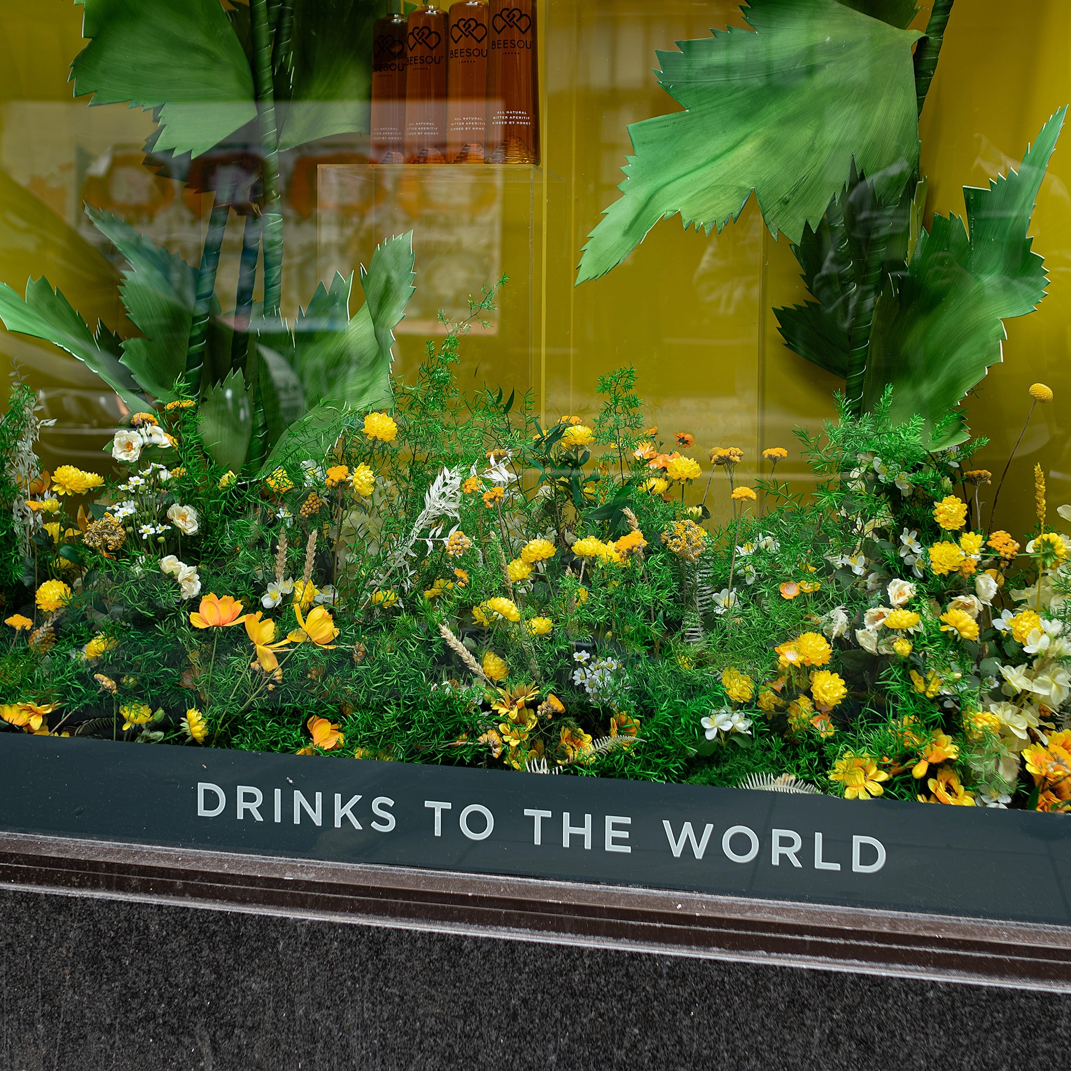 This view of the bespoke floral installation for Beesou offers a view of the rich undergrowth of the flowers and foliage, which perfectly match Beesou's brand colours and create an inviting storefront - Amaranté London.