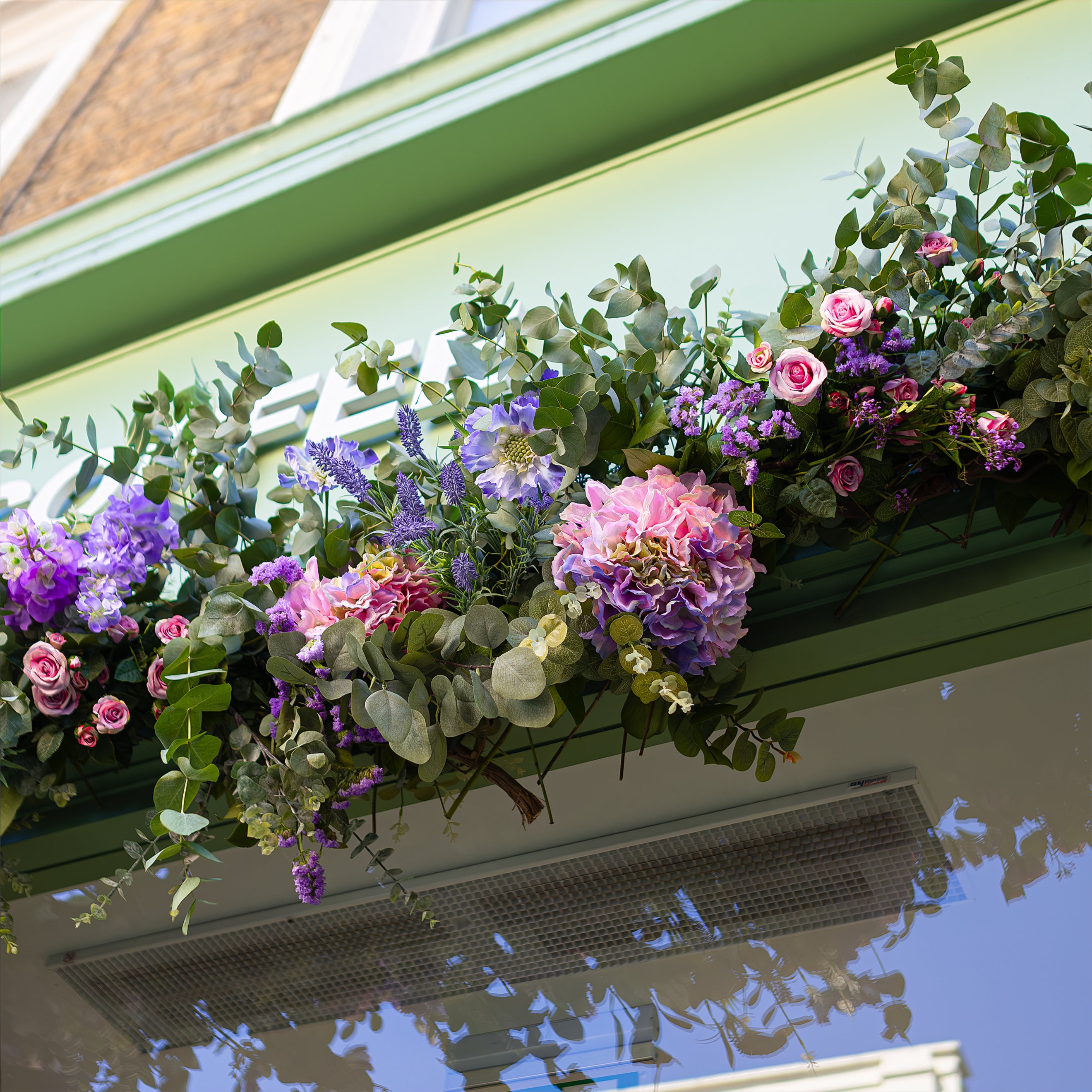 Another view of Amaranté London's floral installation for Blank Street Coffee's storefront features a vibrant mix of pink hydrangeas, purple roses, and lush green foliage. The floral arch beautifully complements the café's exterior, adding a natural elegance for Chelsea in Bloom.