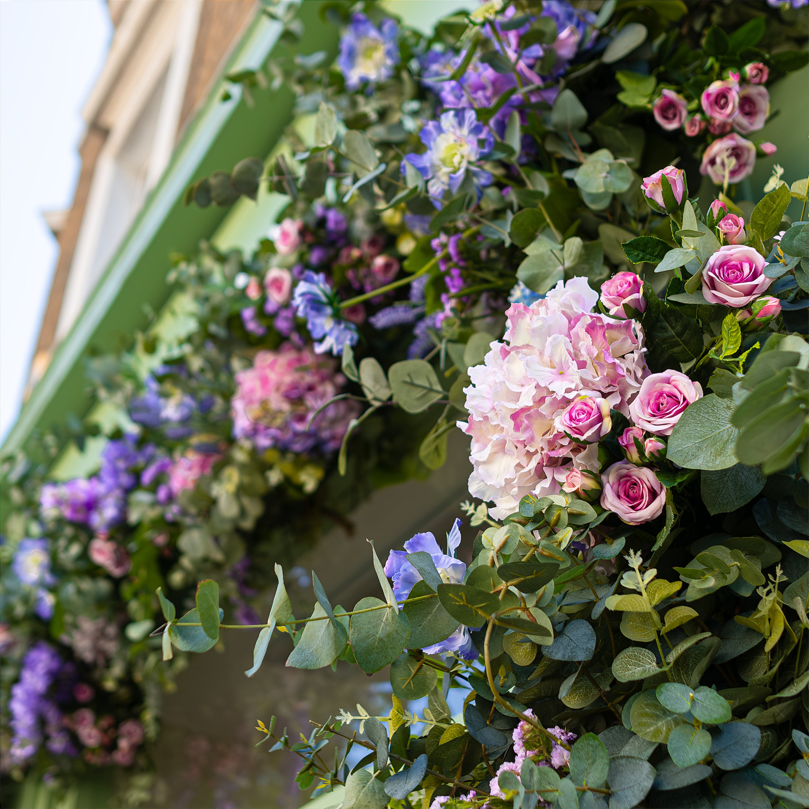 A close-up of the floral décor created by Amaranté London for Blank Street Coffee's participation in Chelsea in Bloom. This detailed view highlights the intricate mix of pink and purple flowers with lush green foliage, perfectly complementing the café's exterior.