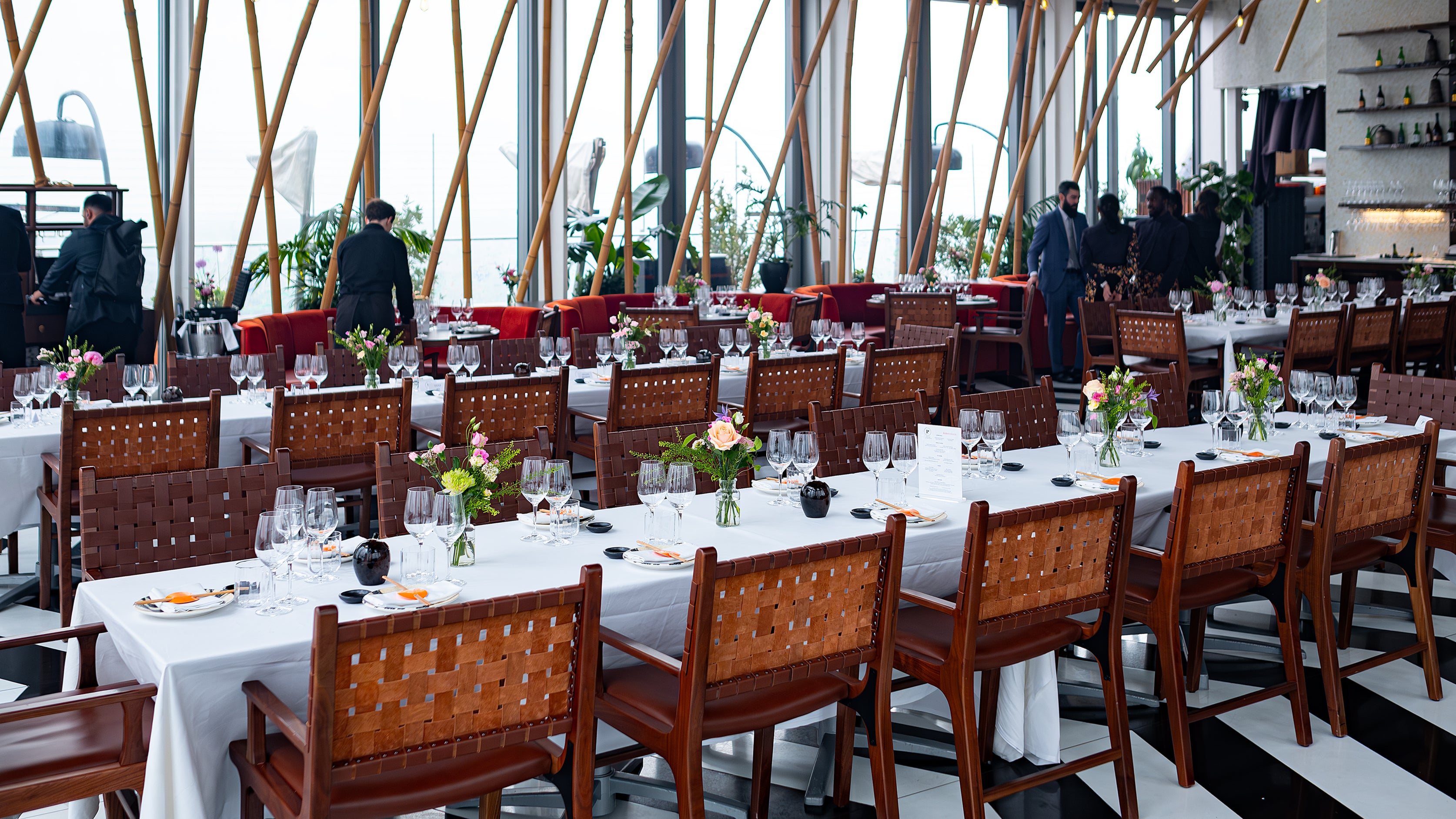 The dining area at SUSHISAMBA prepared for the Chanel event, with bespoke luxury floral arrangements by event florist  Amaranté London. The tables feature pink and cream roses and flowers, creating an elegant and inviting atmosphere for the corporate gathering.