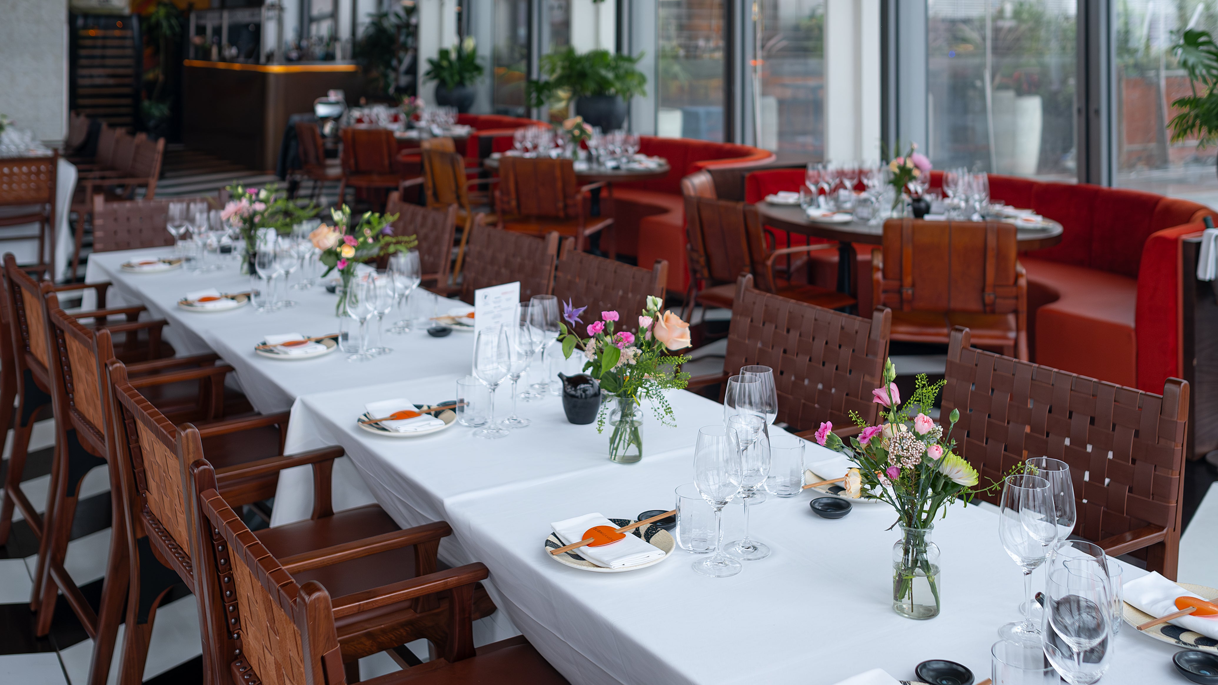 A long dining table at the Chanel event in SUSHISAMBA, adorned with bespoke floral arrangements designed and created by event florist Amaranté London. These luxury bouquets include a mix of pink and cream blooms, perfectly complementing the luxurious setting.