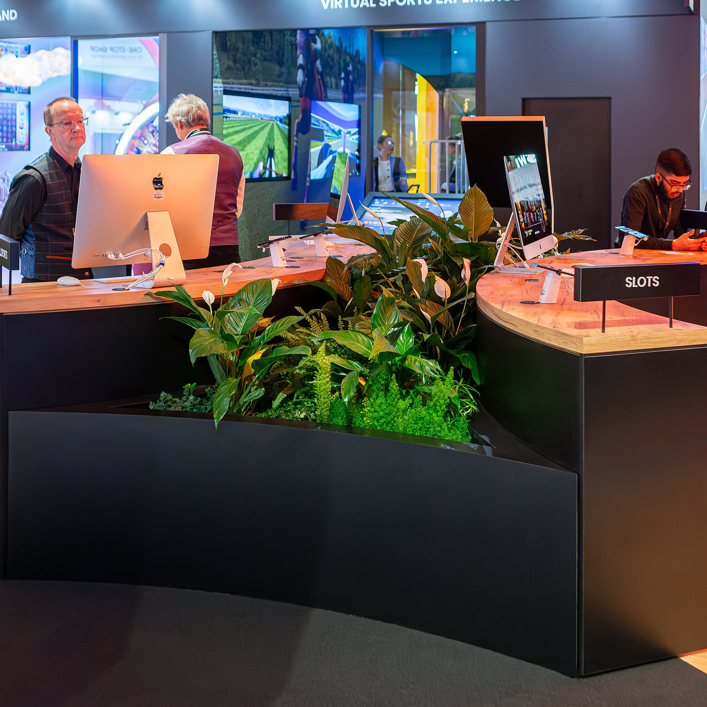 Amarante London Lush green plants decorate a sleek workspace at the ICE London Exhibition, offering a serenity amidst the buzz of virtual sports betting and gaming technology displays.
