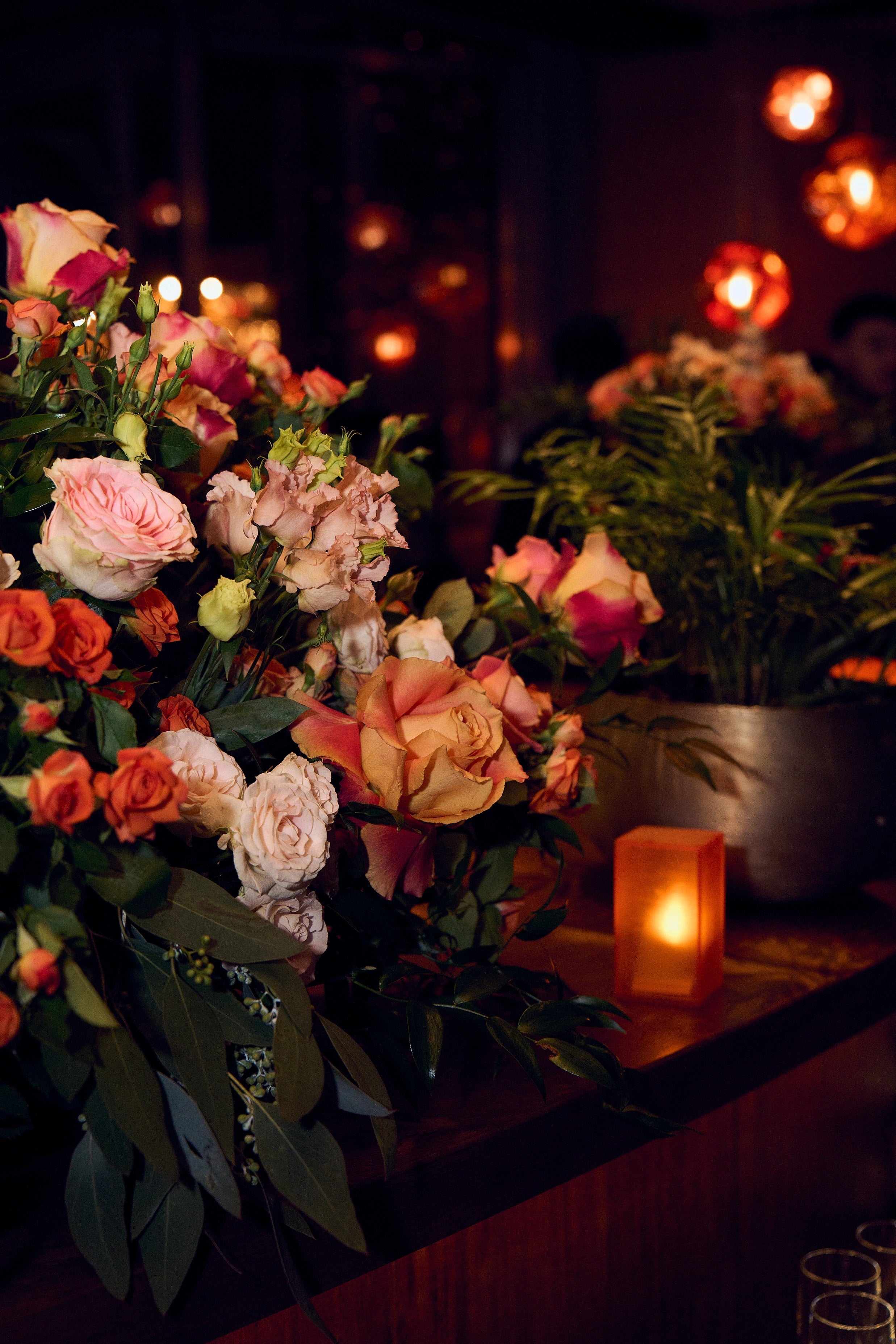 Bespoke floral arrangements are placed at the sides of the entertainment stage, featuring a mix of orange and cream roses with lush greenery designed to complement the luxurious setting of the EasyJet annual partner event in London.