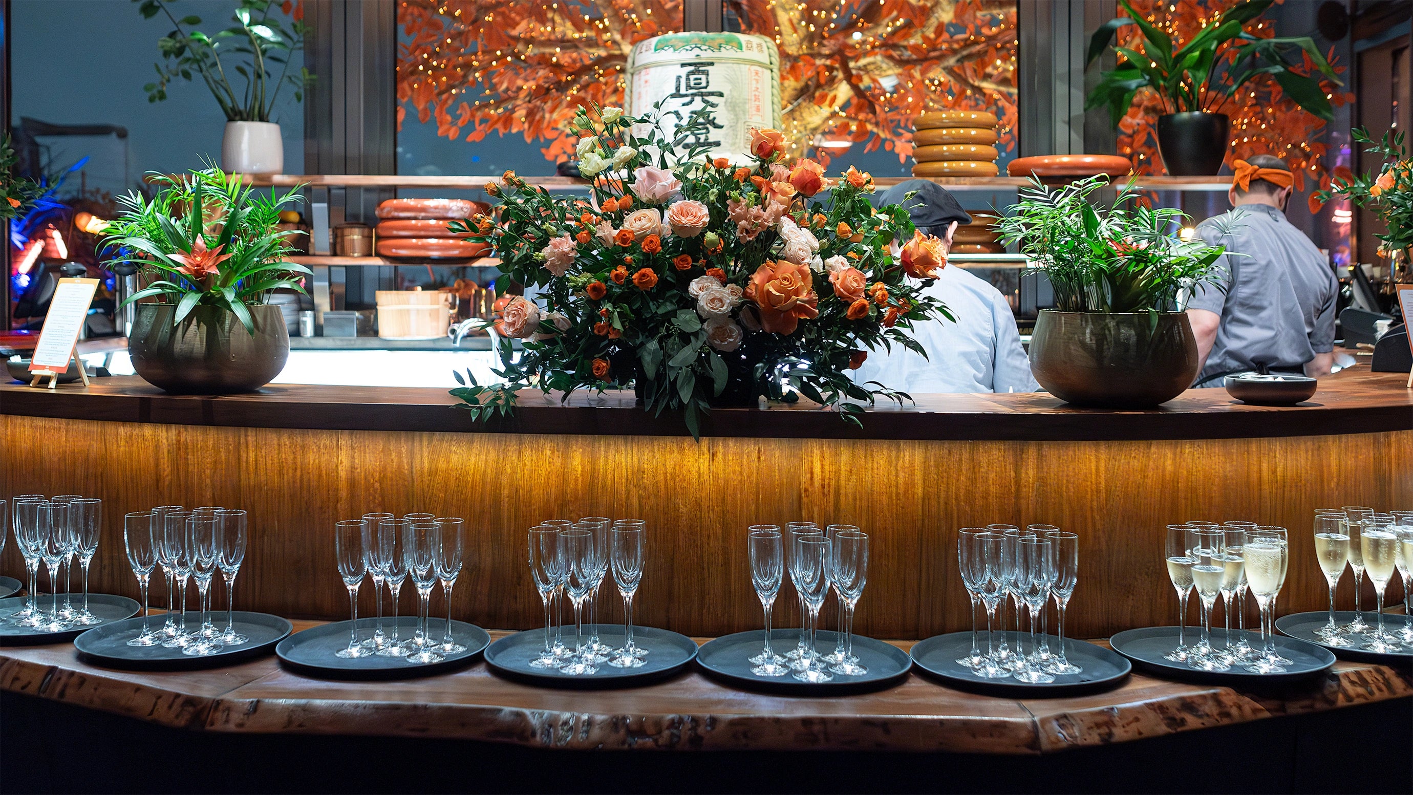 A close-up of a bespoke flower table arrangement with vibrant orange and soft cream roses in a textured glass vase in the luxurious setting of the EasyJet annual partner event in London - AmarantÃ© London