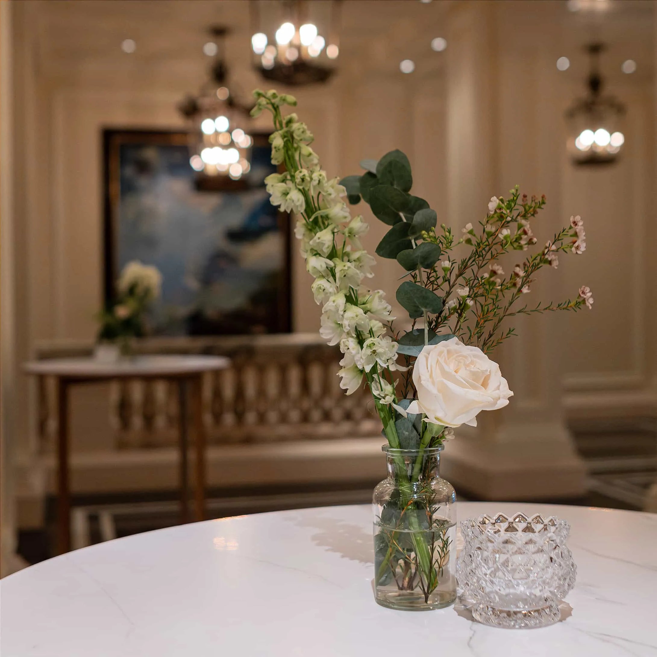 A simple yet elegant floral display by Amaranté London - Event Florist in London. In his image, a single pristine rose and delicate greenery in a clear vase