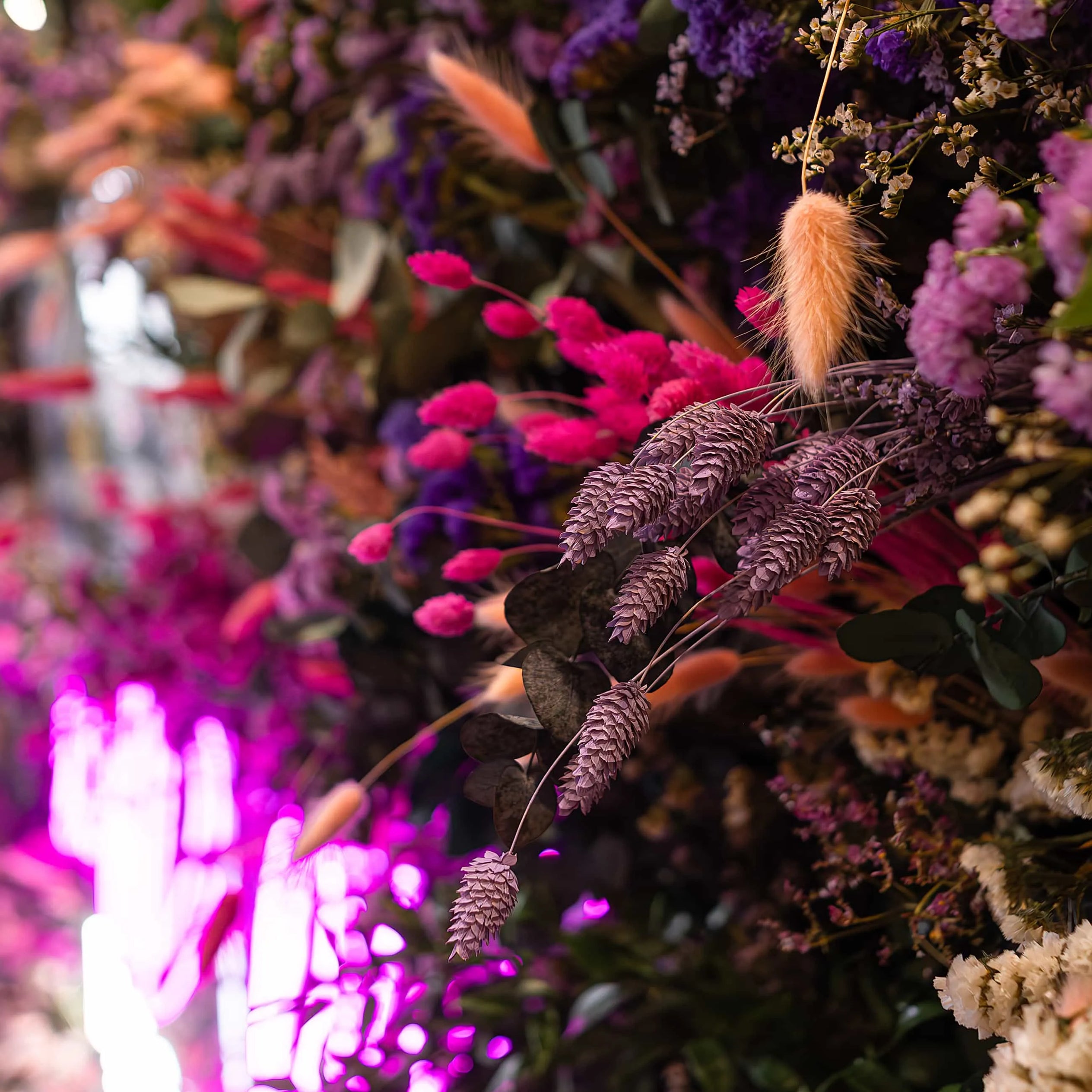 A detailed view of an intricate floral arrangement at the Formula E event, displaying a mix of textured blooms in vivid pinks and purples under ambient lighting - Amaranté London.
