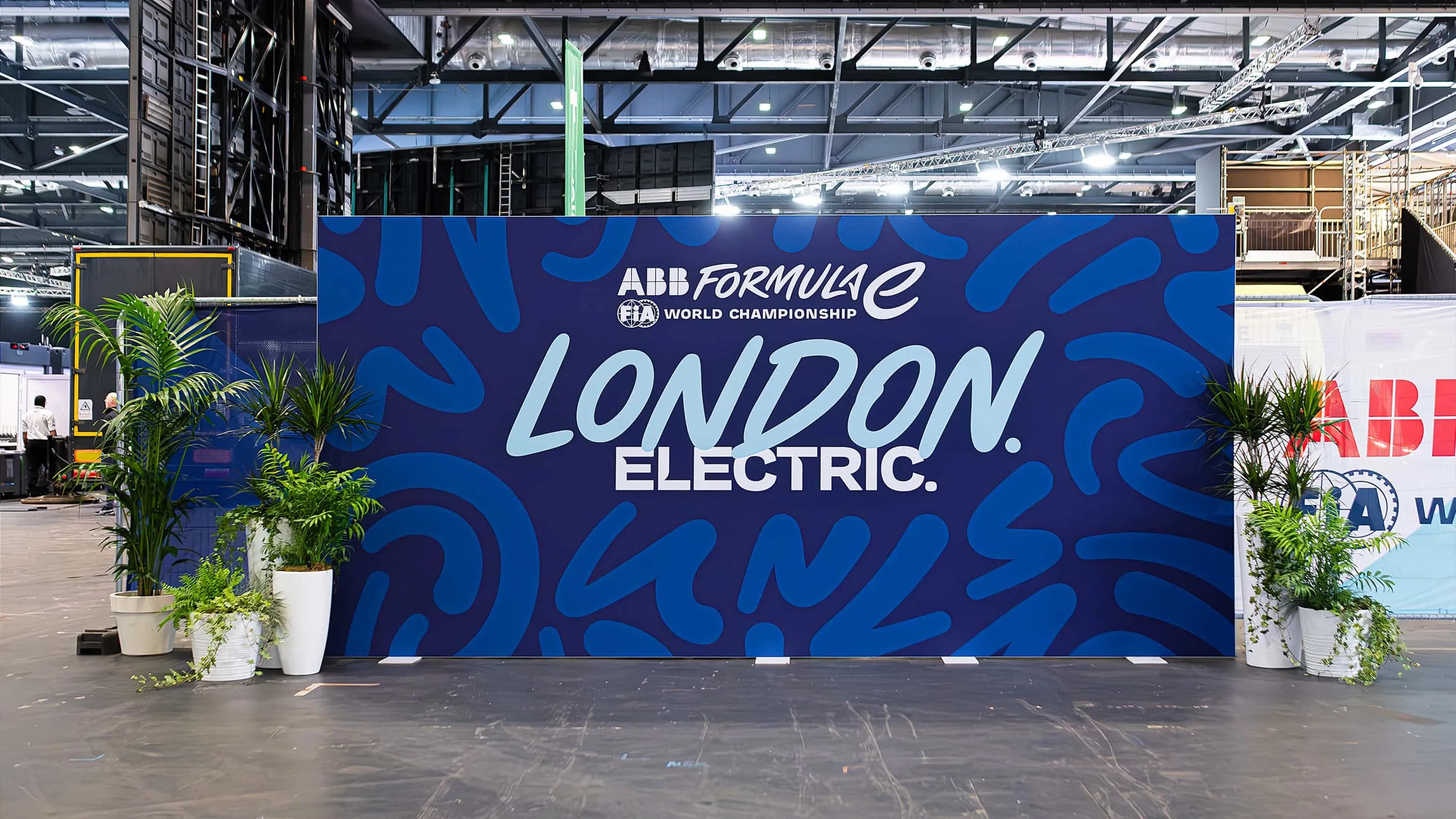 A luxurious and vibrant floral display featuring a mix of purple, pink, and white flowers and plants elegantly adorn the event entrance at the ABB Formula E World Championship in London — Event Floristry by Amaranté London.