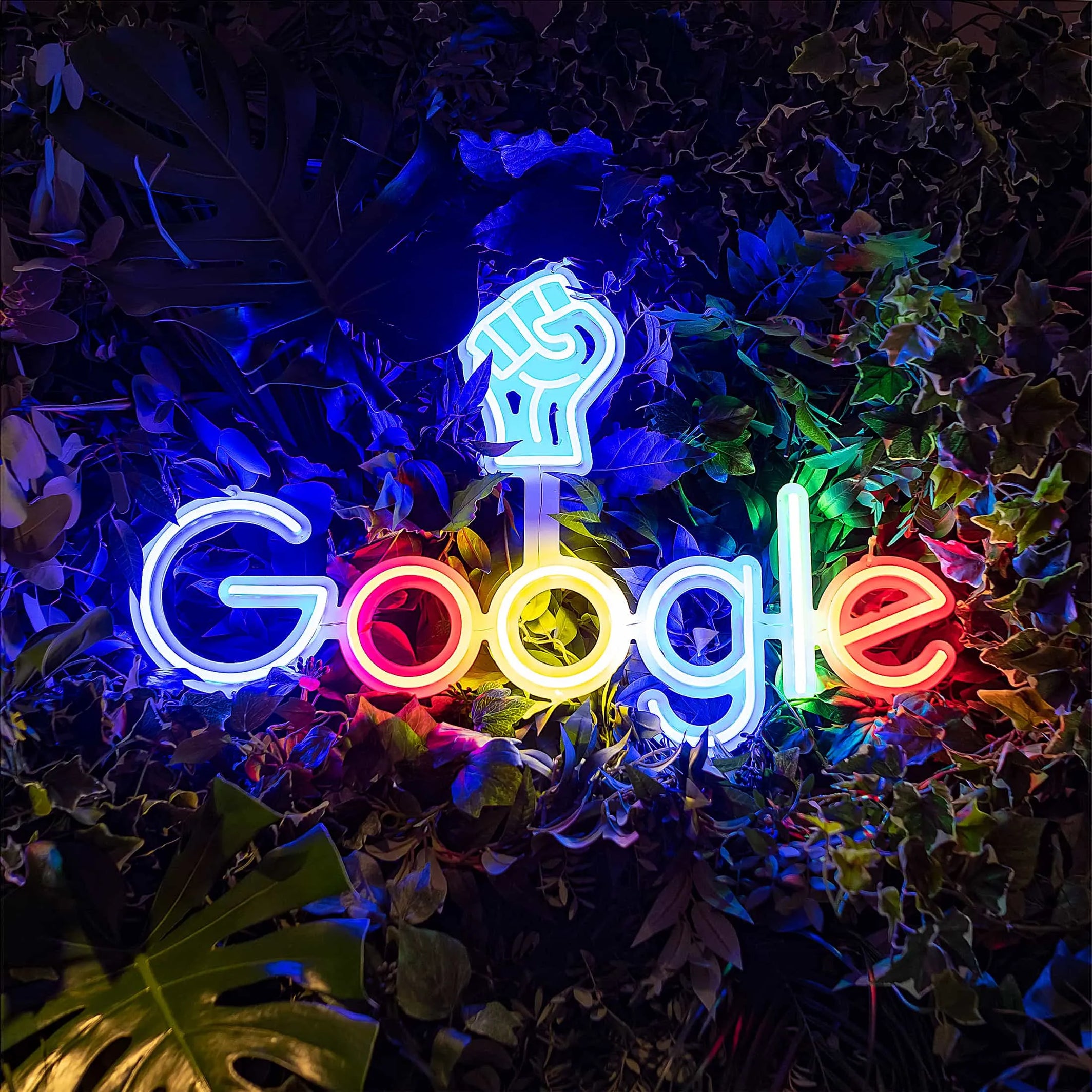 Vibrant close-up of Amaranté London's floral arrangement at Google, showcasing a variety of green shades and textures, highlighted by a glowing Google logo