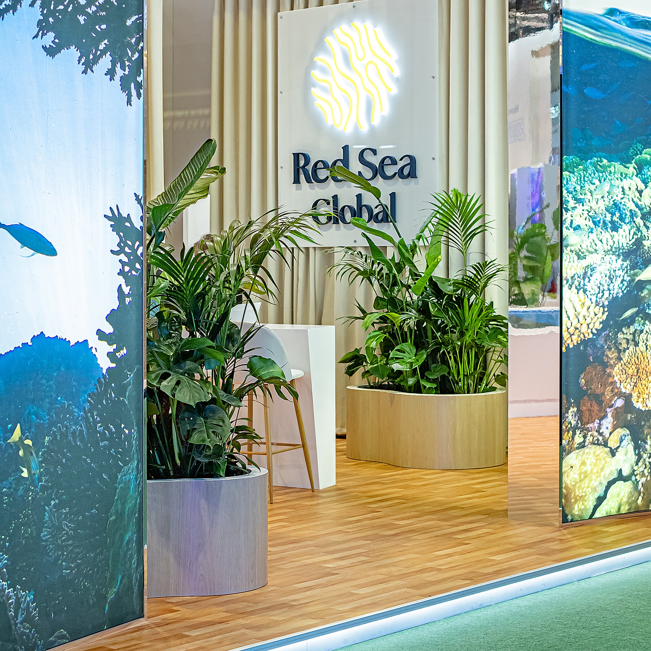 A refined display of Amaranté London's floral arrangements at WTM London for Red Sea Global, a lush, green island specifically for their booth featuring planters creating a serene oasis in the corporate event setting.