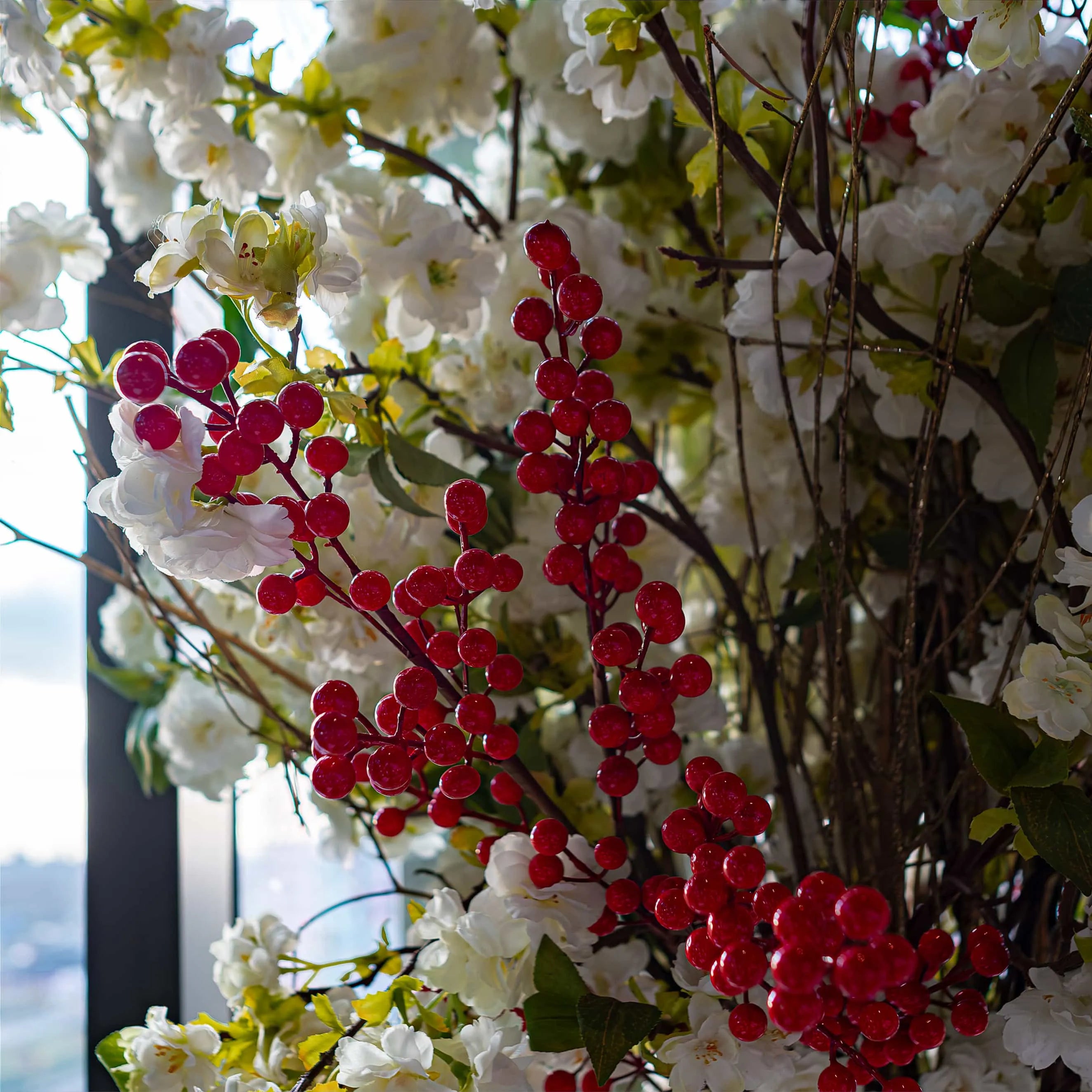 A vibrant spray of cherry red berries stands out among the white flowers and greenery in this Christmas floral arrangement for the STK Steakhouse in London, designed, created, and installed by event florist Amaranté London.