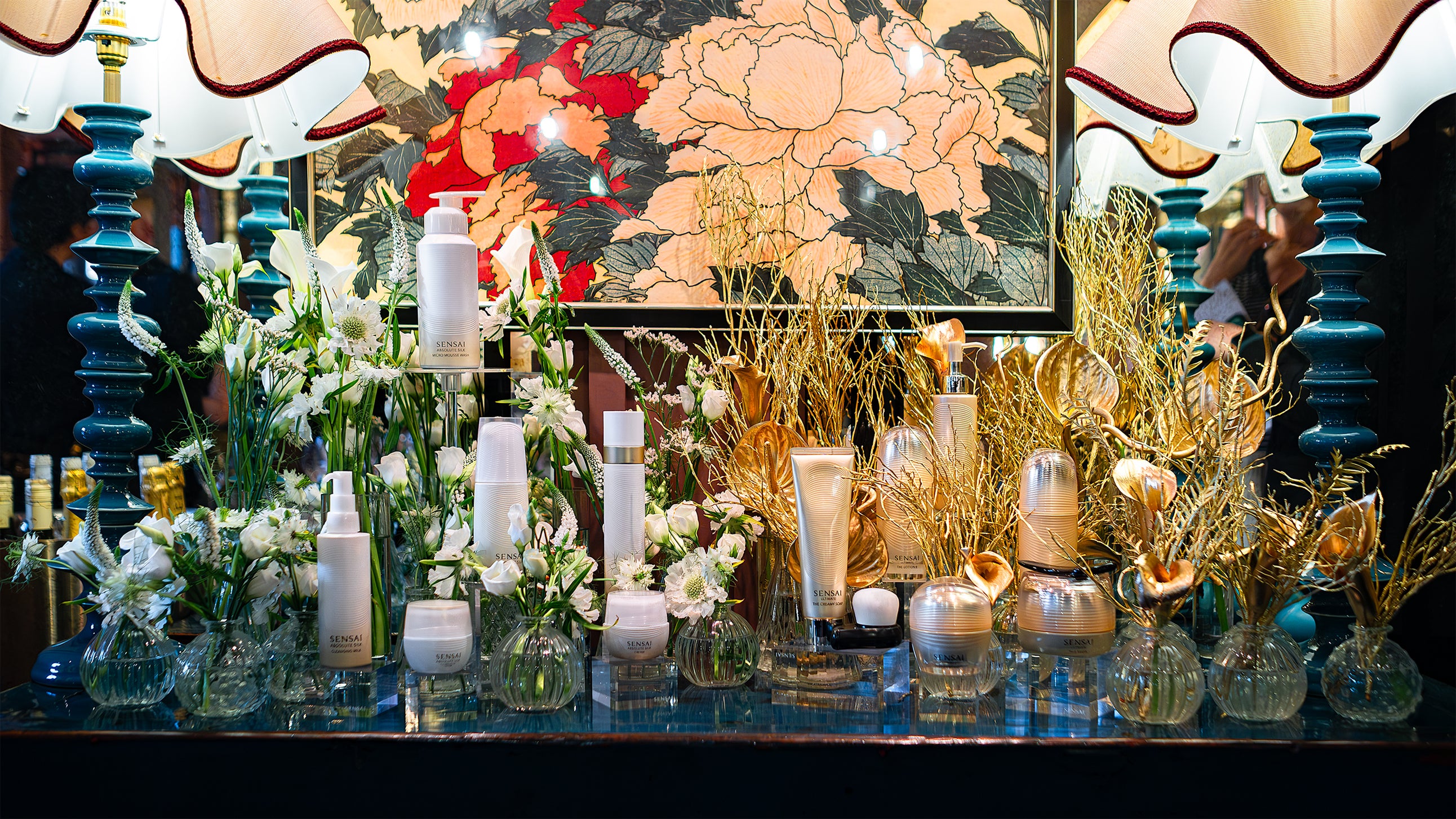 A luxurious display of Sensai skincare products amidst white flower arrangements designed and installed by event florist Amarante London, highlighting the elegance of the Sensai products at their launch at Beaverbrook Town House venue.