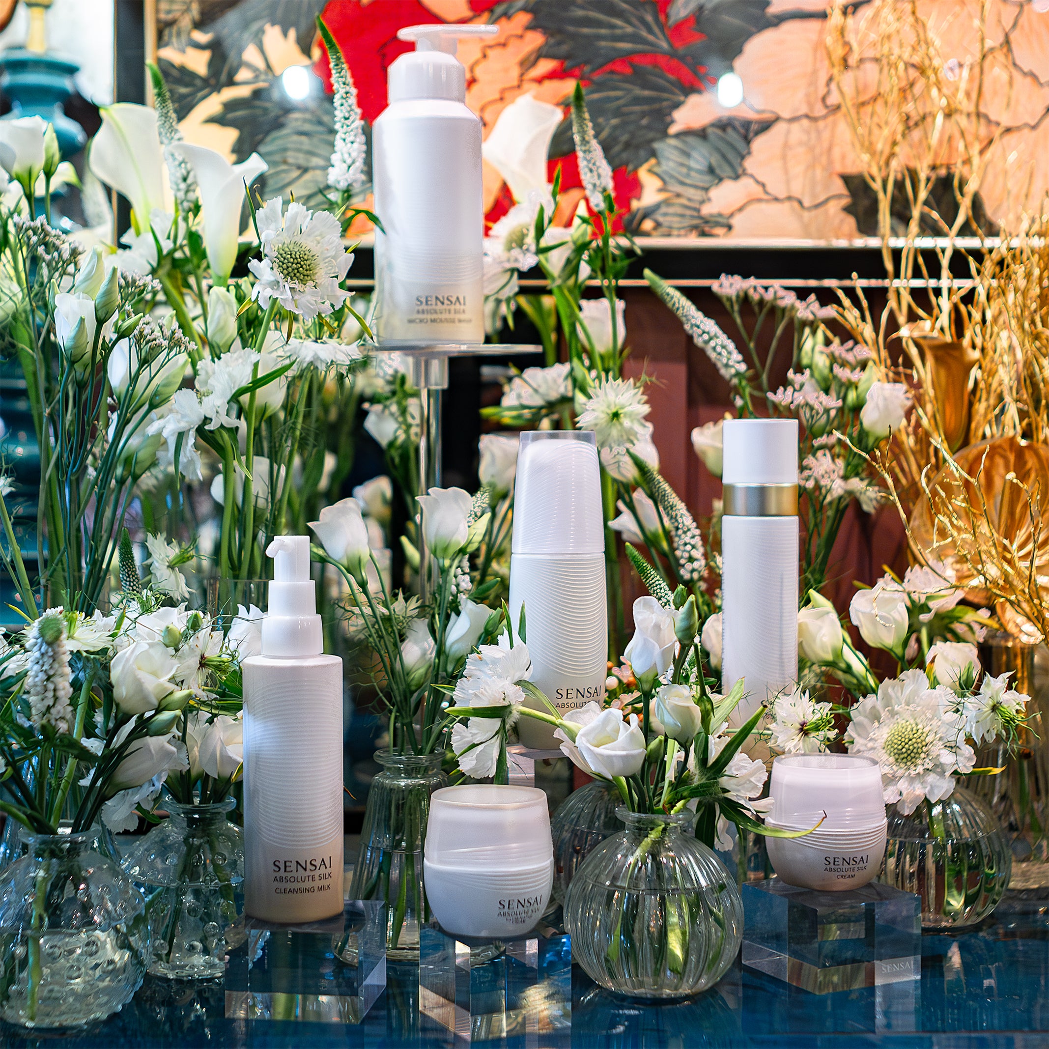 A stunning collection of Sensai skincare products surrounded by elegant white flowers in clear vases, arranged by Amarante London for the product launch.