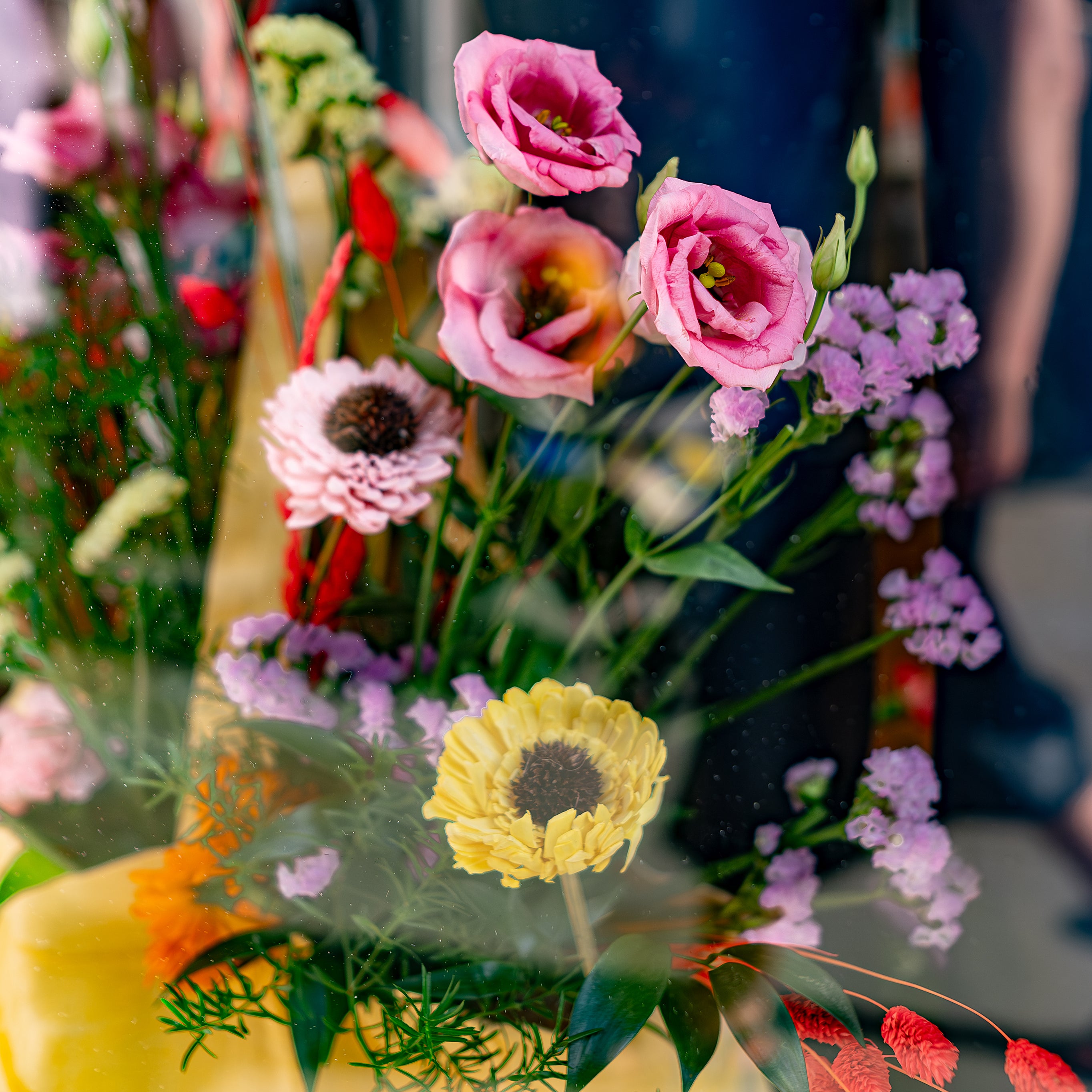 A stunning floral arrangement by Amaranté London featuring pink lisianthus, yellow gerbera daisies, and various greenery, showcased in a vibrant and fresh display at the Vilebrequin store during Chelsea in Bloom.