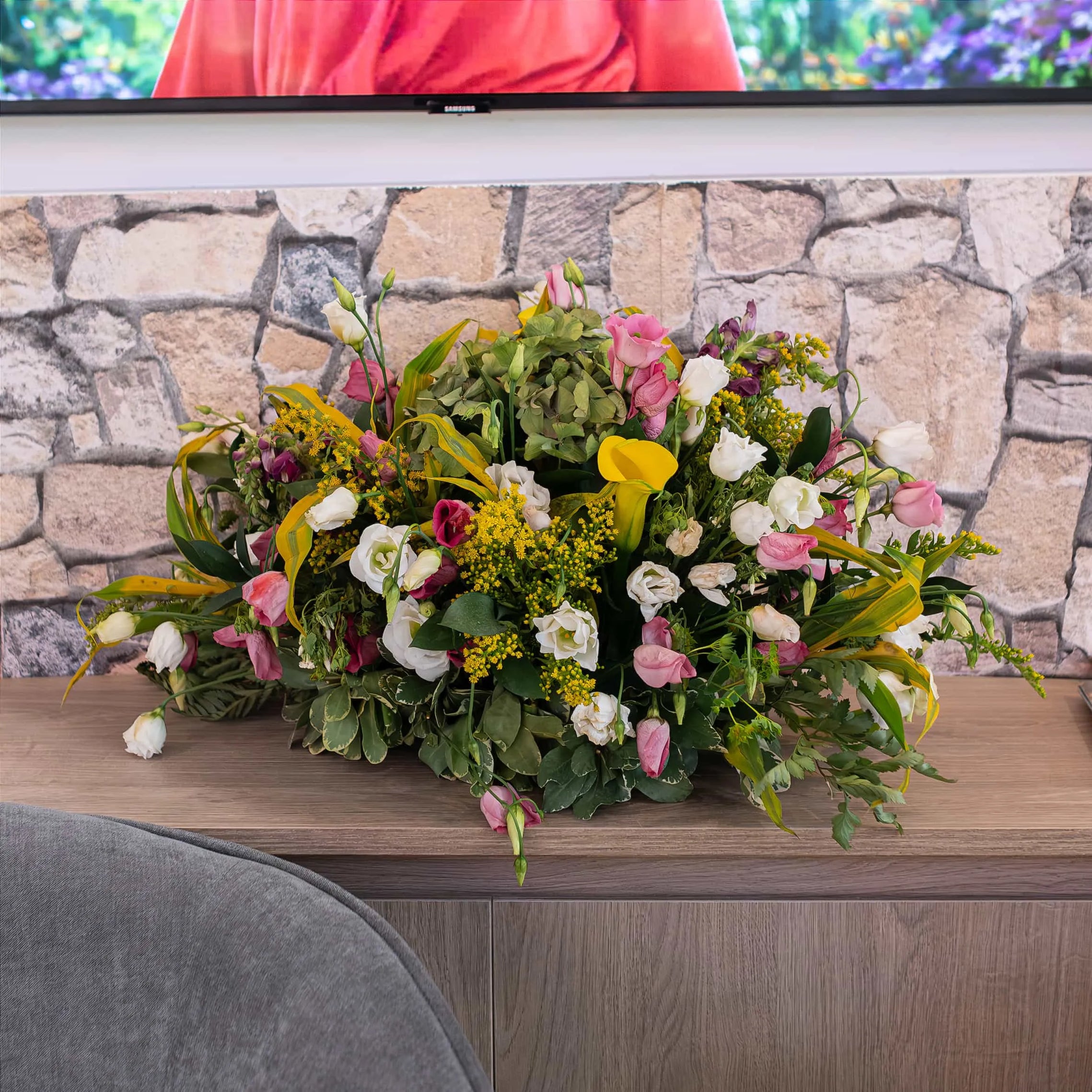 Vibrant mix of fresh flowers - floral arrangement designed by Event Florist Amaranté London for WTM: yellow calla lilies and pink roses on a rustic stone-textured counter.